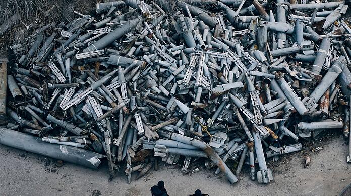 Gewalt auf allen Ebenen: Polizisten stehen in der besonders umkämpften Stadt Charkiw vor einem Berg an Raketenfragmenten, die in der Umgebung eingeschlagen sind.