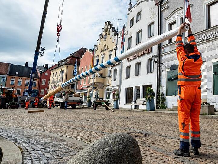 Mit einem Kran wird ein Maibaum am Marktplatz aufgestellt. Foto: Armin Weigel/dpa/Archivbild