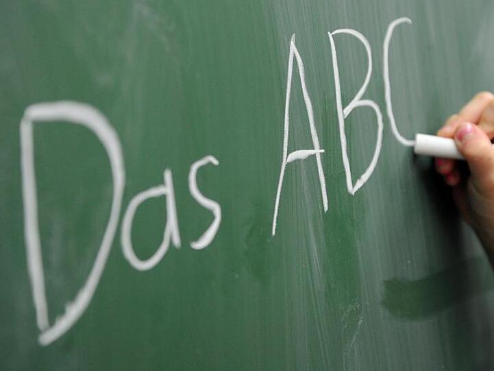 Eine Grundschülerin schreibt das ABC an die Tafel.