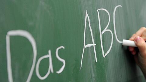 Eine Grundschülerin schreibt das ABC an die Tafel.