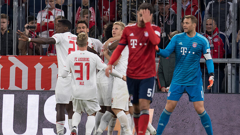 Und da ist es passiert: Die Augsburger jubeln mit Torschütze Felix Götze, Manuel Neuer realisiert, dass der Treffer auf seine Kappe geht.