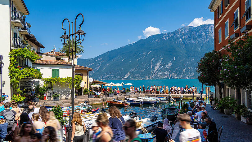 Touristen an der Uferpromenade in Limone sul Garda am Westufer des Gardasees. Der ist mit dem Zug wegen eines Streiks in Italien womöglich nur eingeschränkt zu erreichen.