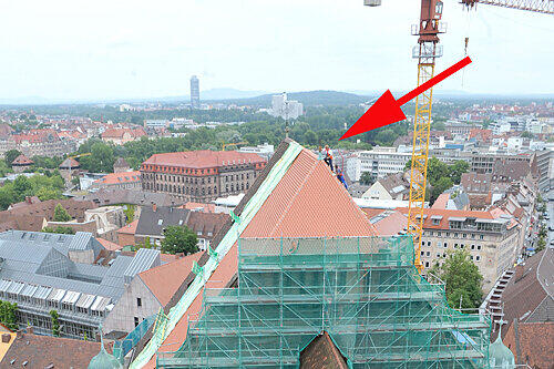 Gesichert mit einem Seil setzt Spenglermeister Michael Haneck das &bdquo;Lausbubenkäpple&ldquo; auf das Dach der Lorenzkirche...