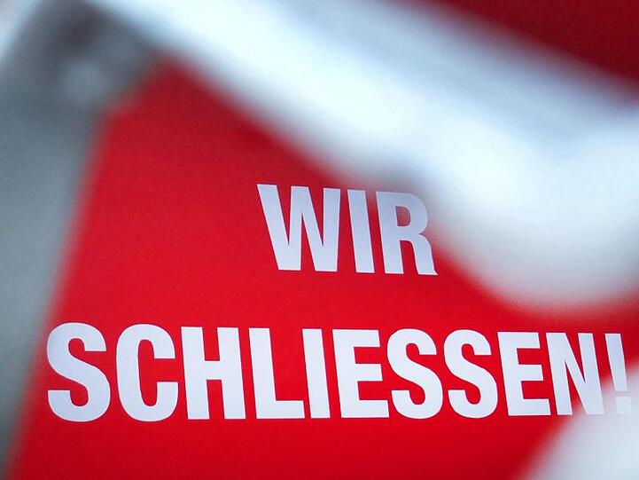 "Wir schließen!" steht hinter einem Rollgitter an einem geschlossenen Geschäft in Düsseldorf.
