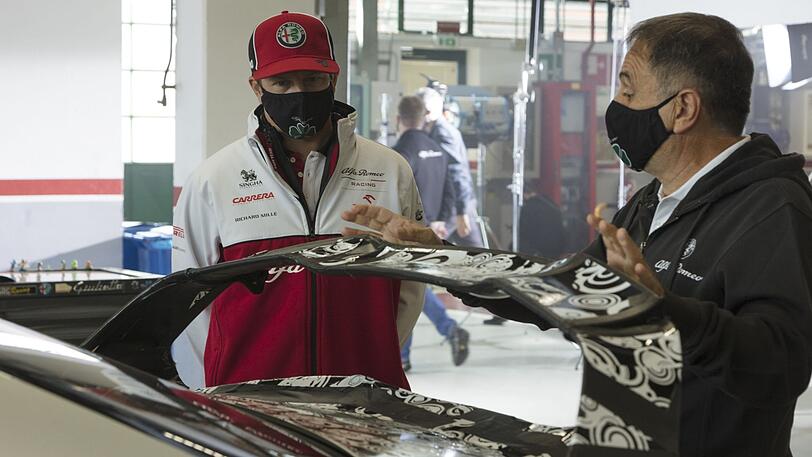 Kimi Räikkönen diskutiert mit einem Aerodynamik-Experten von Alfa Romeo über den neuen Heckspoiler.