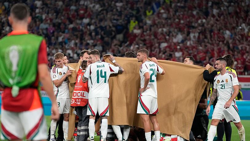 Die ungarischen Spieler halten einen Sichtschutz, während Stürmer Barnabas Varga behandelt wird.
