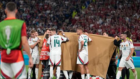 Die ungarischen Spieler halten einen Sichtschutz, während Stürmer Barnabas Varga behandelt wird.