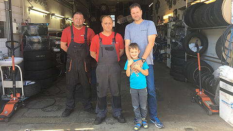 Reifenhändler Dominik Senjek (rechts) mit seinem Sohn und zwei Mechanikern vor seiner Werkstatt.