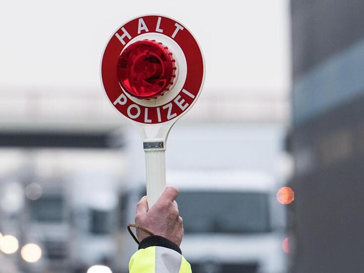 Ein Polizeibeamter hält eine Polizeikelle hoch. Foto: Soeren Stache/Archiv