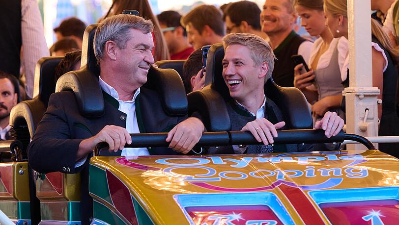Markus S&ouml;der (CSU), Ministerpr&auml;sident von Bayern, und Dominik Krause (B&uuml;ndnis 90/ Die Gr&uuml;nen), Oberb&uuml;rgermeister von M&uuml;nchen, fahren anl&auml;sslich der Nominierung M&uuml;nchens als deutscher Olympia-Bewerber auf dem Oktoberfest zusammen mit der Achterbahn &bdquo;Olympia Looping&ldquo;.