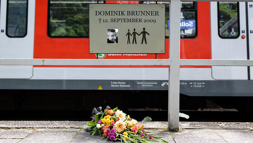 Frische Blumen mit einer Trauerschleife liegen am zehnten Jahrestag des Verbrechens unter der Gedenktafel in Solln.