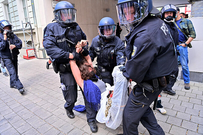 Eine Protestteilnehmerin wird während einer Demonstration gegen die IAA von Polizisten weggetragen.