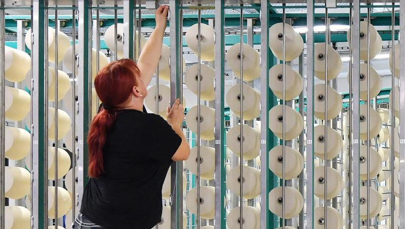 Eine Mitarbeiterin bestückt in der Getzner Textilweberei GmbH die sogenannte Zettelmaschine mit Garn. Foto: Martin Schutt/Archiv Eine Mitarbeiterin bestückt in der Getzner Textilweberei GmbH die sogenannte Zettelmaschine mit Garn. Foto: Martin Schutt/Archiv