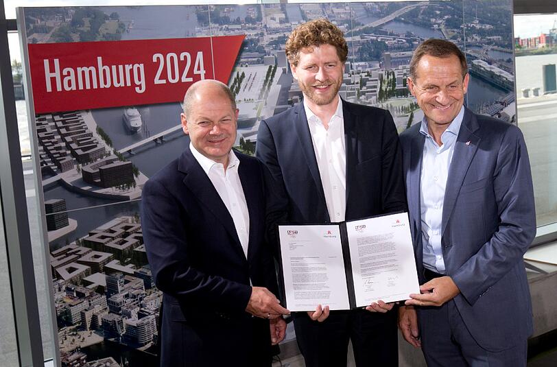 Hamburgs Erster Bürgermeister Olaf Scholz (SPD), DOSB-Präsident Alfons Hörmann (r) und Nikolas Hill (m), Geschäftsführer der Bewerbungsgesellschaft Hamburg 2024, präsentieren die unterzeichnete Ankündigung der Bewerbungsunterlagen zur Kandidatur um die Bewerbung für Olympische und Paralympische Spiele 2024 in der Hansestadt.
