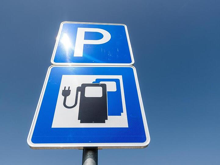 Ein Hinweisschild für Parkplätze mit Ladestationen für Elektroautos steht am Schnellladepark einer Autobahn-Raststätte.