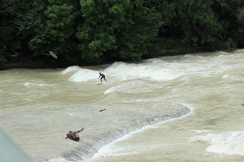 Hochwasser für die einen, perfekte Wellen für die anderen. Waghalsig tummeln sich Sportler in der Isar.