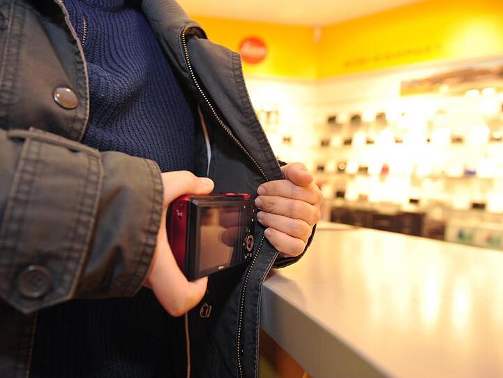 Eine Frau steckt eine Kamera in ihre Jacke. Foto: Jan-Philipp Strobel/dpa