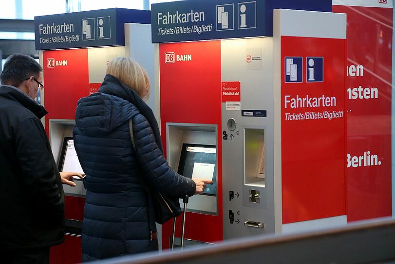 Reisende buchen an einem Automaten der Deutschen Bahn eine Zugfahrkarte.