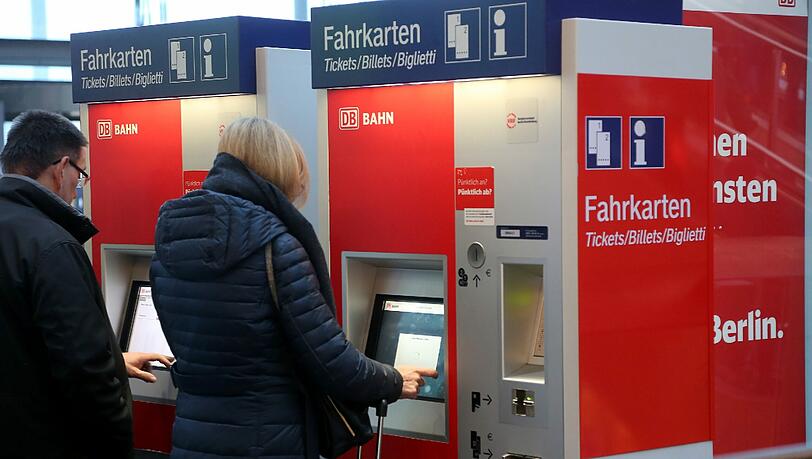 Reisende buchen an einem Automaten der Deutschen Bahn eine Zugfahrkarte. Reisende buchen an einem Automaten der Deutschen Bahn eine Zugfahrkarte.