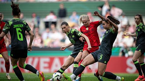 Wolfsburgs Jule Brand (l) und Lena Oberdorf kämpfen mit Bayerns Pernille Harder um den Ball.