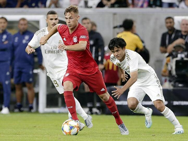 Joshua Kimmich (M) setzt sich am Bell gegen Karim Benzema (l) und Takefusa Kubo von Real Madrid durch.