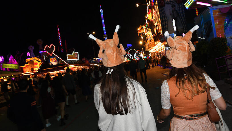Zwei Damen mit Hendl-H&uuml;ten gehen bei Nacht &uuml;ber das Oktoberfest.