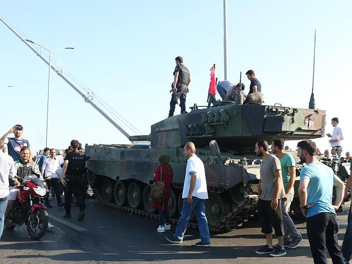 Türkische Polizisten und Anhänger von Präsident Erdogan stehen nach dem gescheiterten Putsch in der Nähe von Panzern auf der Bosporusbrücke in Istanbul.
