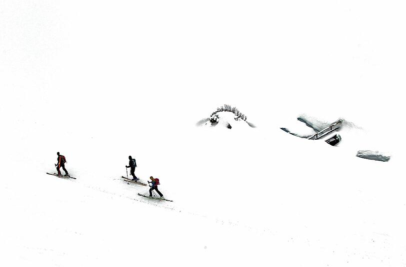 Drei Tourengeher marschieren durch die tief verschneite Landschaft auf dem Fellhorn bei Oberstdorf. Ski-Touren auf und abseits der Pisten boomen.