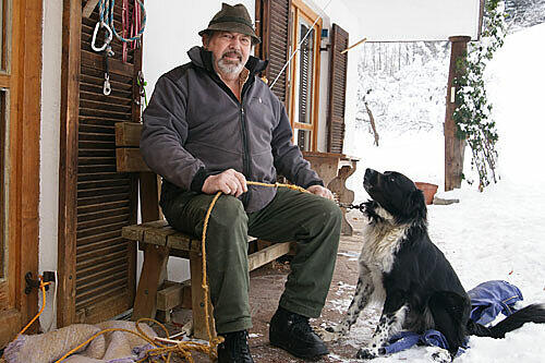 Kann dieser Mann Olympia stoppen? Theo Geyer, Bauer aus Garmisch, mit seinem mittelzärtlichen Hund Baschi vor seinem Haus. &bdquo;Mir wern behandelt, als wär ma gar net do.&ldquo;