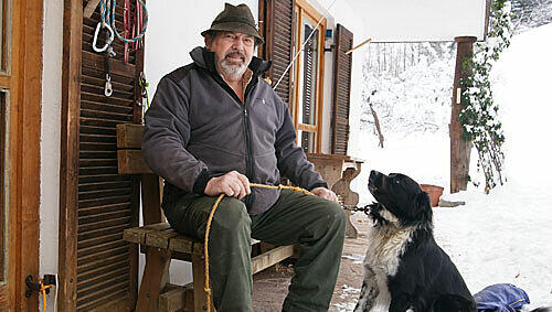 Kann dieser Mann Olympia stoppen? Theo Geyer, Bauer aus Garmisch, mit seinem mittelzärtlichen Hund Baschi vor seinem Haus. &bdquo;Mir wern behandelt, als wär ma gar net do.&ldquo;