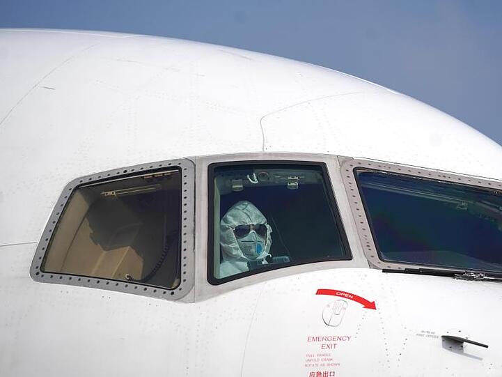 Ein Pilot sitzt mit Schutzanzug und Maske im Cockpit und parkt ein Flugzeug auf dem Internationalen Flughafen Wuhan-Tianhe.