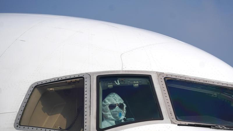 Ein Pilot sitzt mit Schutzanzug und Maske im Cockpit und parkt ein Flugzeug auf dem Internationalen Flughafen Wuhan-Tianhe. Ein Pilot sitzt mit Schutzanzug und Maske im Cockpit und parkt ein Flugzeug auf dem Internationalen Flughafen Wuhan-Tianhe.