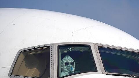 Ein Pilot sitzt mit Schutzanzug und Maske im Cockpit und parkt ein Flugzeug auf dem Internationalen Flughafen Wuhan-Tianhe.