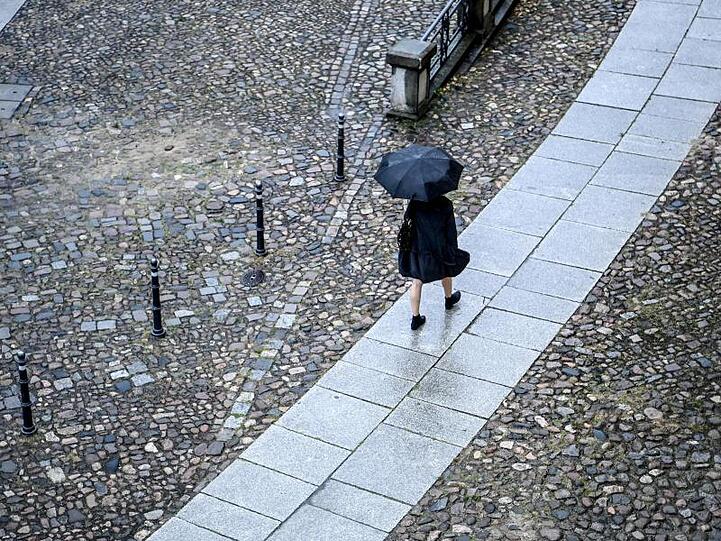 Eine Frau geht bei Regen eine Straße entlang. Foto: Britta Pedersen/dpa-Zentralbild/dpa/Symbolbild