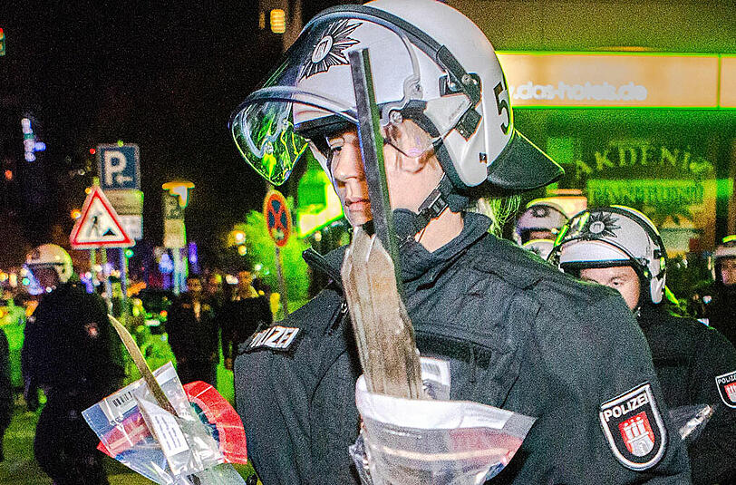 Eine Polizistin trägt aufgefundene Hieb- und Stichwaffen zu einem Fahrzeug.
