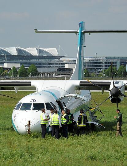 Mitarbeiter des Flughafens in München betrachten die Maschine der italienischen Fluggesellschaft, die am Donnerstag auf dem Münchner Flughafen notlanden musste. Das Flugzeug mit 62 Menschen an Bord hatte kurz nach dem Start in Richtung Venedig umdrehen müssen, weil sich Rauch in der Kabine entwickelt hatte. Bei der Landung wurden fünf Personen leicht verletzt, die Maschine kam neben der Landebahn zum Stehen.