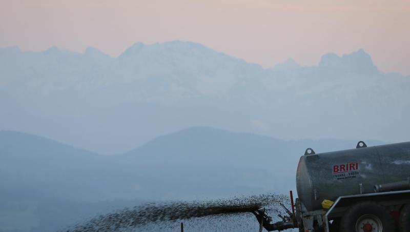 Ein Landwirt düngt auf dem 1055 Meter hohen Auerberg vor dem Panorama der Alpen eine Wiese mit Gülle. Ein Landwirt düngt auf dem 1055 Meter hohen Auerberg vor dem Panorama der Alpen eine Wiese mit Gülle.