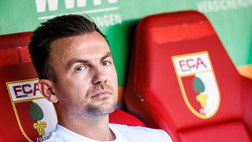 Trainer Enrico Maaßen von Augsburg sitzt vor Spielbeginn auf der Bank.