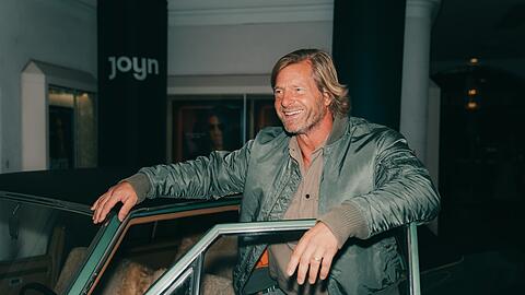 Henning Baum alias Mick Brisgau greift wieder an - im Münchner Gloria Palast posiert der 53-Jährige am Montag mit seinem grünen Kult-Opel.