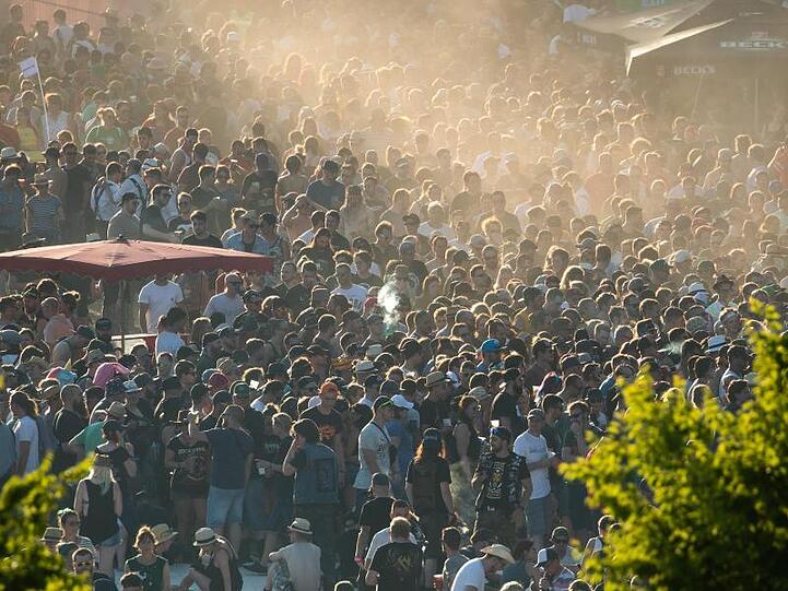 Besucher des Open-Air-Festivals "Rock im Park" gehen über Festival-Gelände in der Abendsonne. Foto: Daniel Karmann