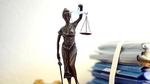 Die modellhafte Nachbildung der Justitia steht in einem Raum neben einem Holzhammer und einem Aktenstapel. Foto: Volker Hartmann/Archivbild