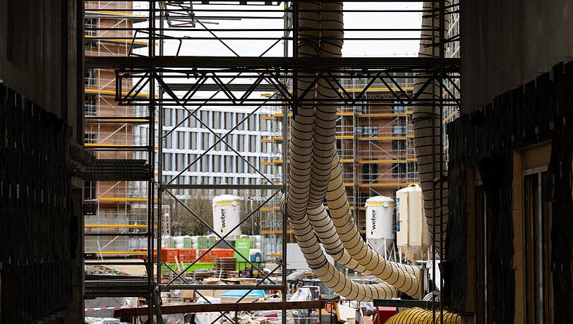 Ein Gerüst und Baumaterial sind auf der Baustelle eines Neubaus zu sehen.