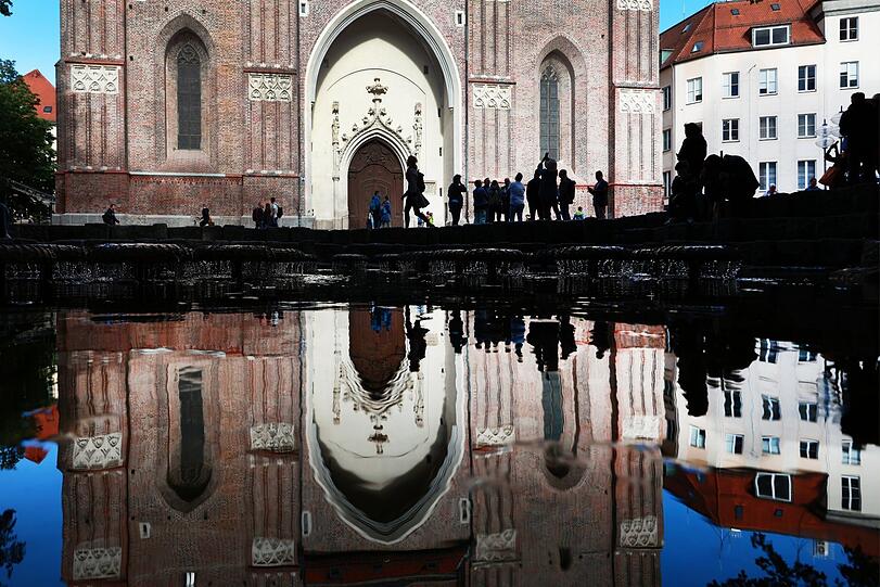 Wasserspiel vor dem Hauptportal der Frauenkirche mit Touristen - das Gleiche noch mal als Spiegelung in der Wasserfläche des Wasserpilzbrunnens.