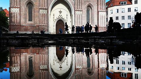 Wasserspiel vor dem Hauptportal der Frauenkirche mit Touristen - das Gleiche noch mal als Spiegelung in der Wasserfläche des Wasserpilzbrunnens.