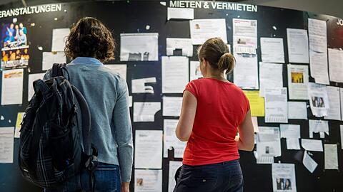 Zwei Studentinnen suchen unter Wohnungsanzeigen am Schwarzen Brett der LMU-Mensa die Nadel im Heuhaufen: eines der wenigen Mietangebote. Größtenteils hängen hier Mietgesuche.