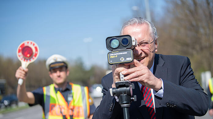Bayerns Innenminister Joachim Herrmann (CSU), steht bei einer Kontrollstelle beim Blitzmarathon hinter einem Geschwindigkeitsmessgerät. An diesem Mittwoch ist es in Bayern wieder so weit.