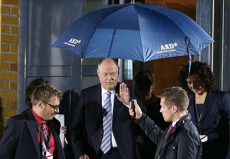 Unter einem Regenschirm verlässt Peer Steinbrück das TV-Studio.