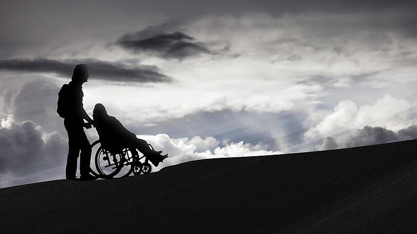 Eine Pflegekraft schiebt einen Patienten mit dem Rollstuhl auf einen Berg &ndash; eine schöne Idee, für die die meisten Pfleger jedoch keine Zeit haben dürften. Jetzt haben Union und SPD mehr Personal angekündigt.
