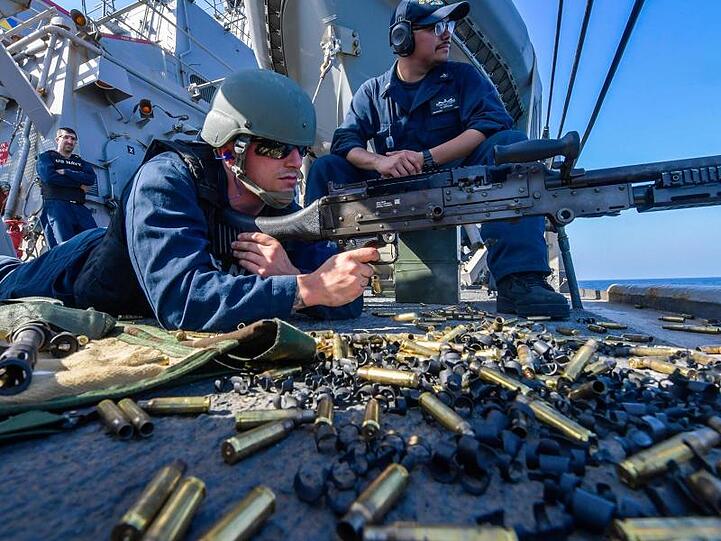 An Bord des Zerstörers "USS Mitscher" im Golf von Oman hält ein US-Soldat ein Maschinengewehr im Anschlag.