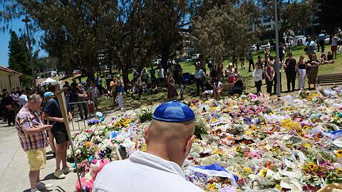 Menschen legen bei einer Gedenkfeier f&uuml;r die Opfer eines Terrorangriffs am Bondi Beach in Sydney Blumen nieder. (Foto aktuell)